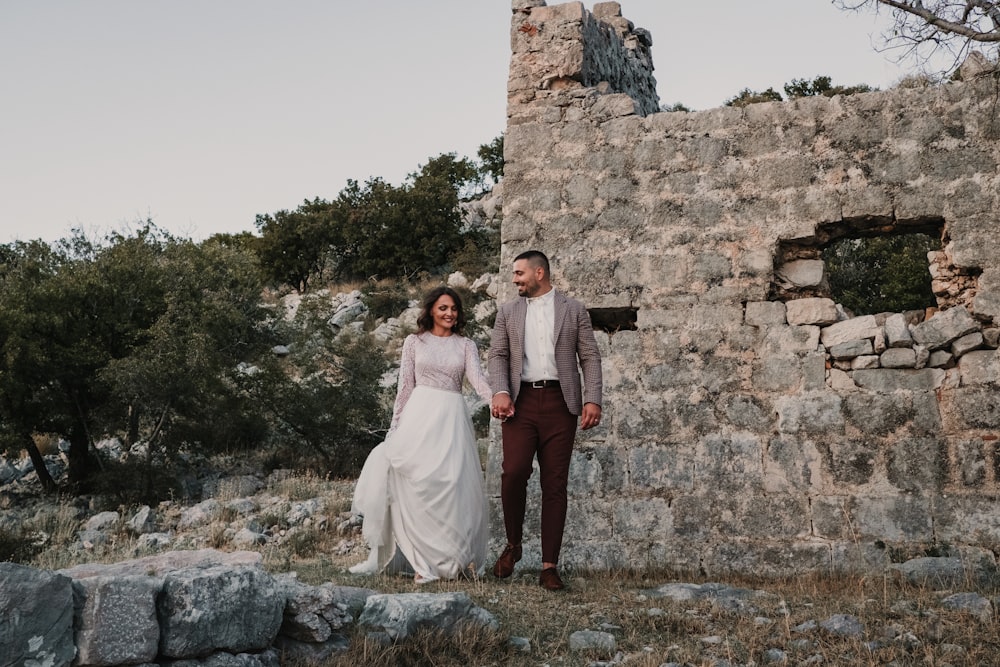 a man and a woman holding hands in front of a stone building