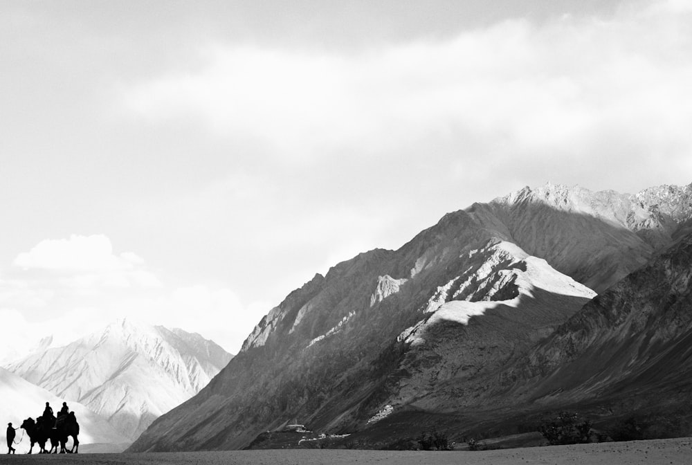 a group of people riding horses through a mountain range