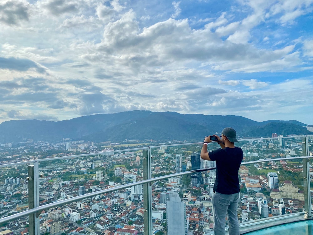 a man taking a picture of a city from a high rise