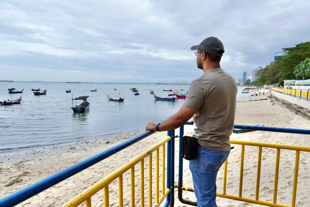 a man standing on a railing looking at boats in the water