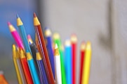 a cup full of colored pencils sitting on top of a table