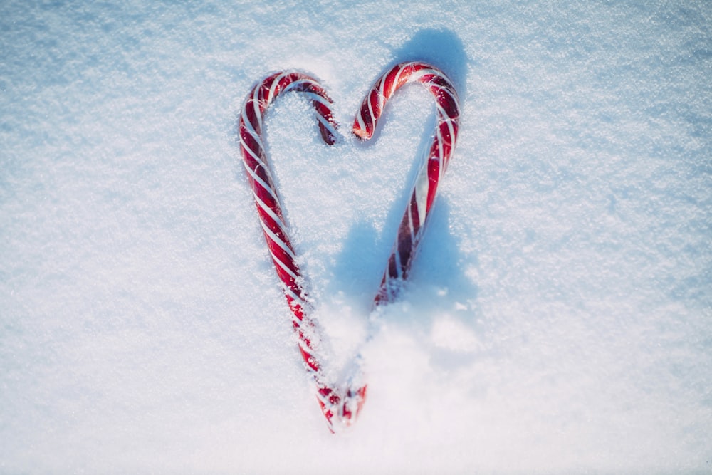 a candy cane in the snow shaped like a heart