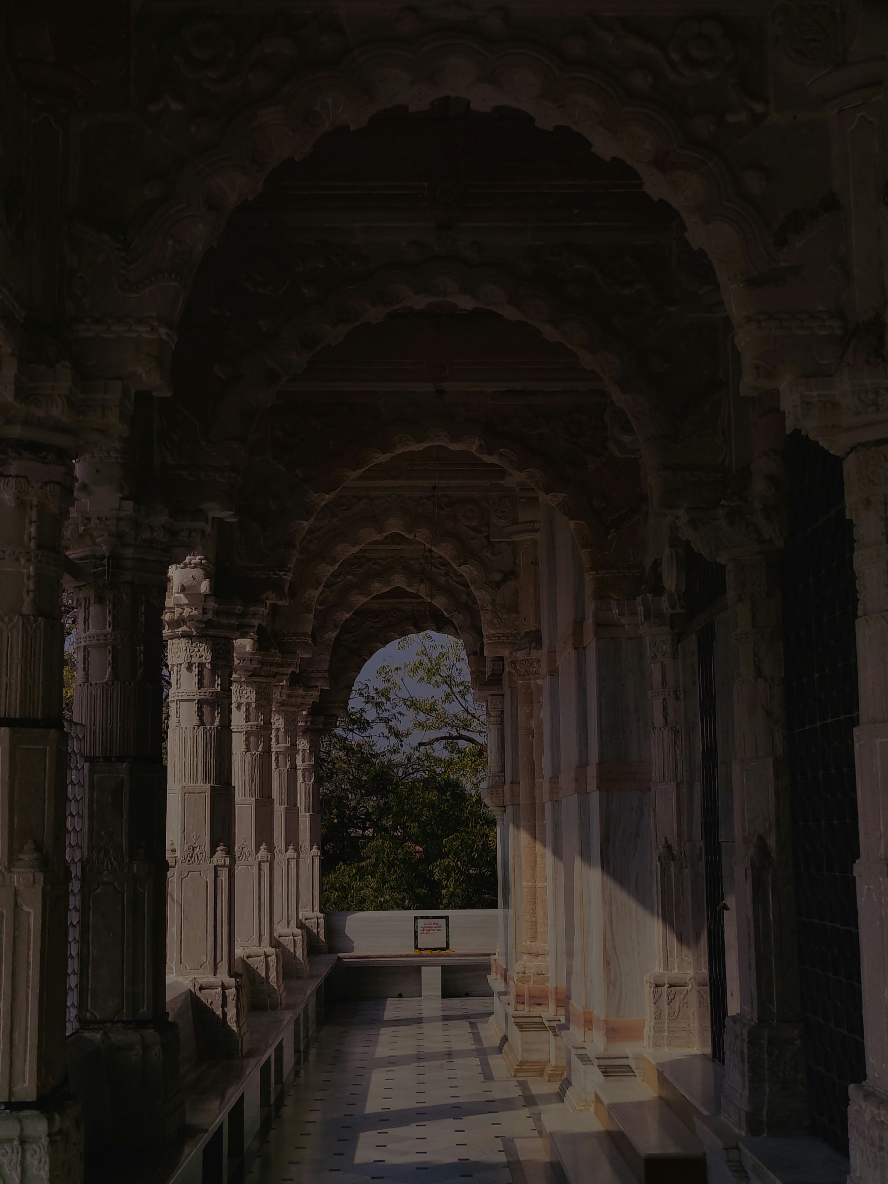 a long hallway with columns and a bench