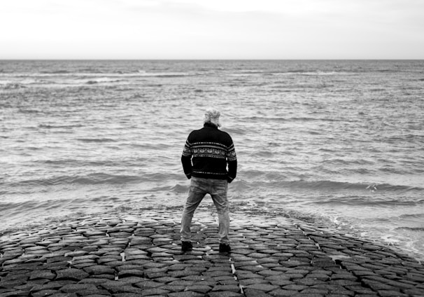 a man standing on top of a stone pier next to the ocean