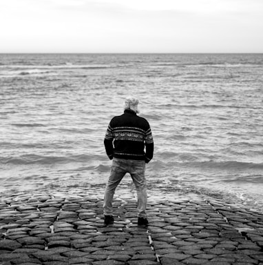 a man standing on top of a stone pier next to the ocean