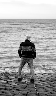 a man standing on top of a stone pier next to the ocean