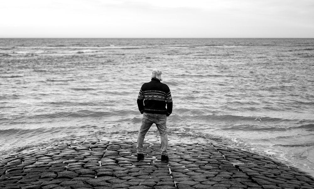 海の横の石の桟橋の上に立つ男