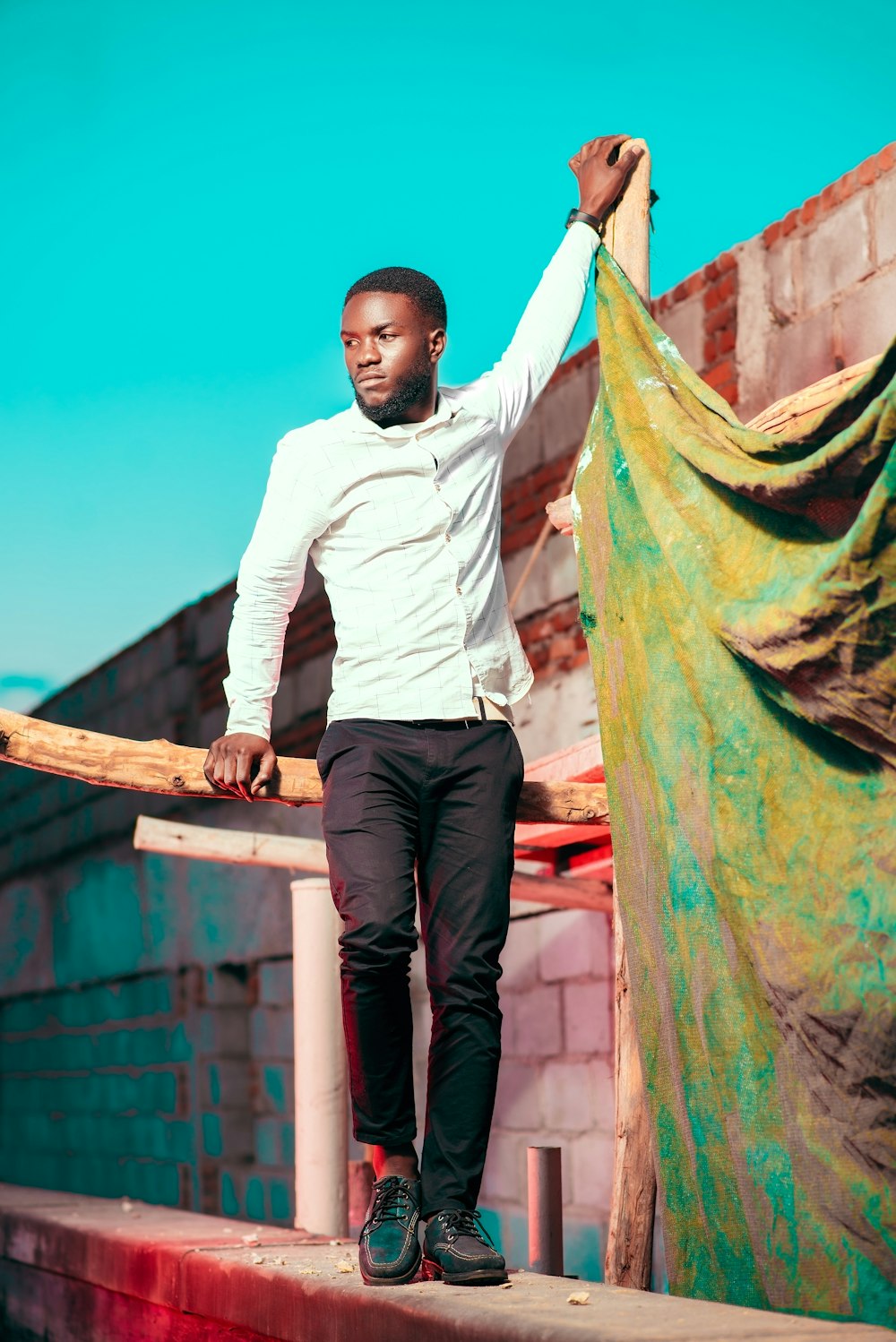 a man standing on a ledge holding a wooden stick