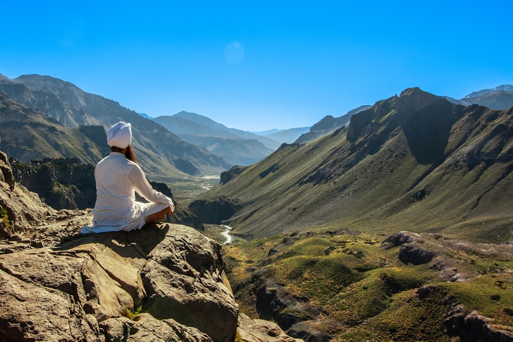 a person sitting on a rock looking out over a valley