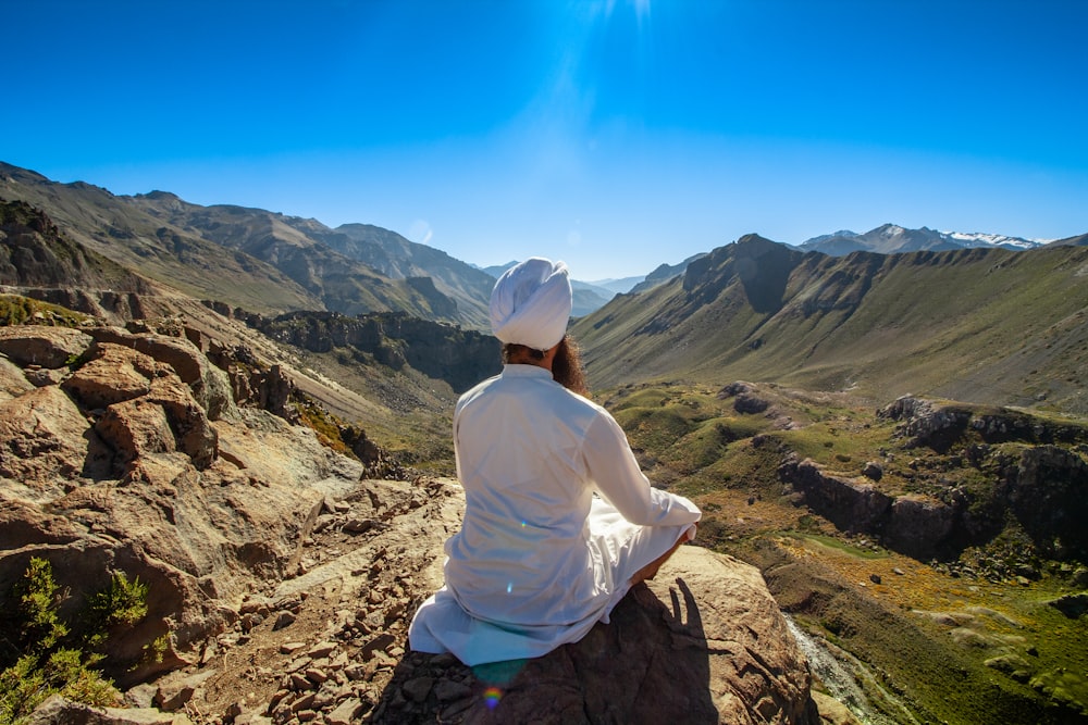 a person sitting on a rock in the mountains