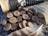 A set of wooden discs featuring engraved runes is scattered on a textured surface. A small pouch made of burlap lies nearby, along with a feather displaying brown and white patterns. A leather-bound horn is partially visible in the background.
