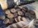 A set of wooden discs featuring engraved runes is scattered on a textured surface. A small pouch made of burlap lies nearby, along with a feather displaying brown and white patterns. A leather-bound horn is partially visible in the background.