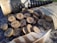 A set of wooden discs featuring engraved runes is scattered on a textured surface. A small pouch made of burlap lies nearby, along with a feather displaying brown and white patterns. A leather-bound horn is partially visible in the background.