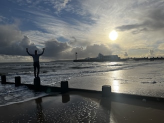 Winner crossing the finish line with arms raised in triumph on the beach.