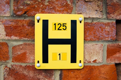a yellow and black sign on a brick wall