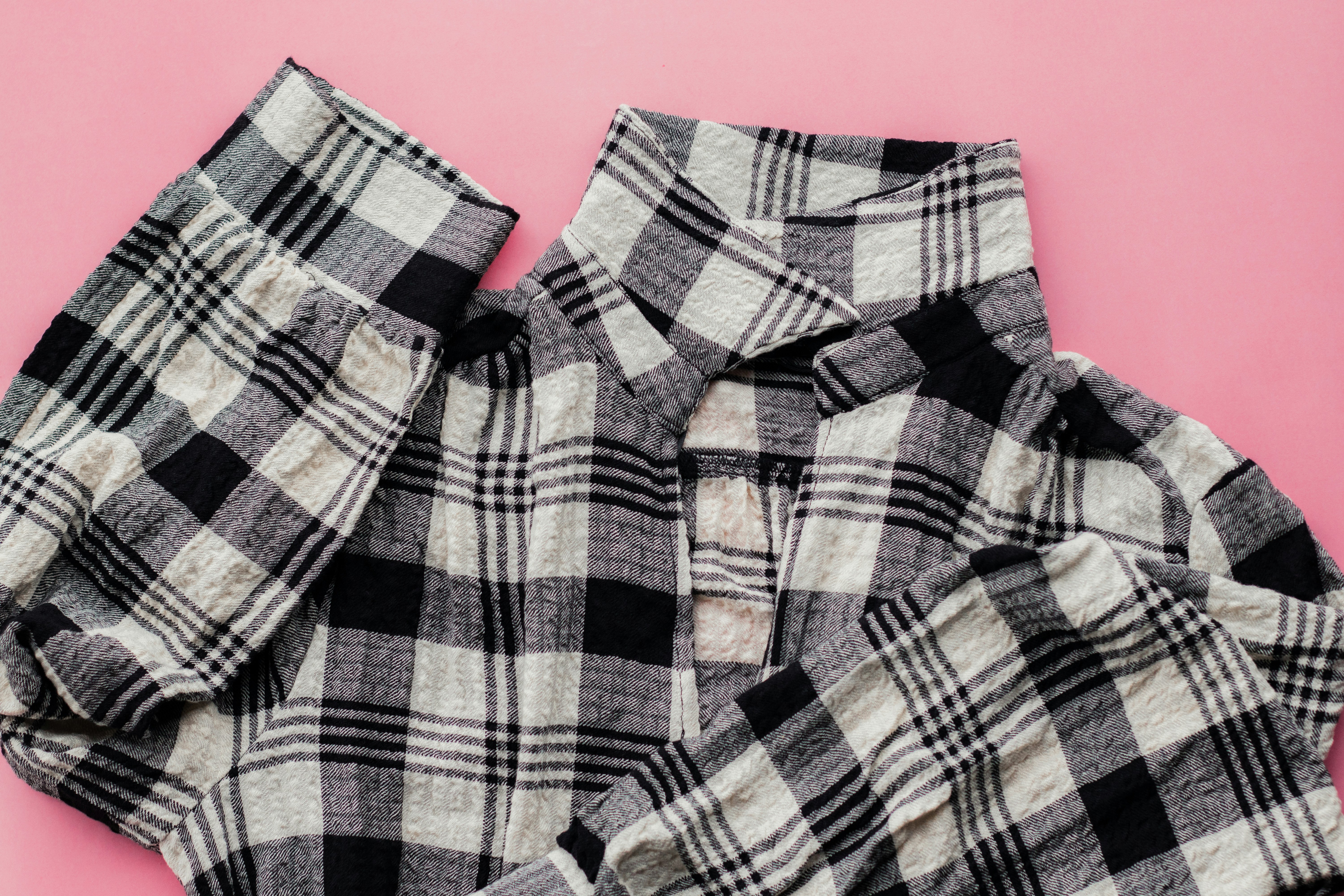 a pair of black and white plaid pants on a pink background