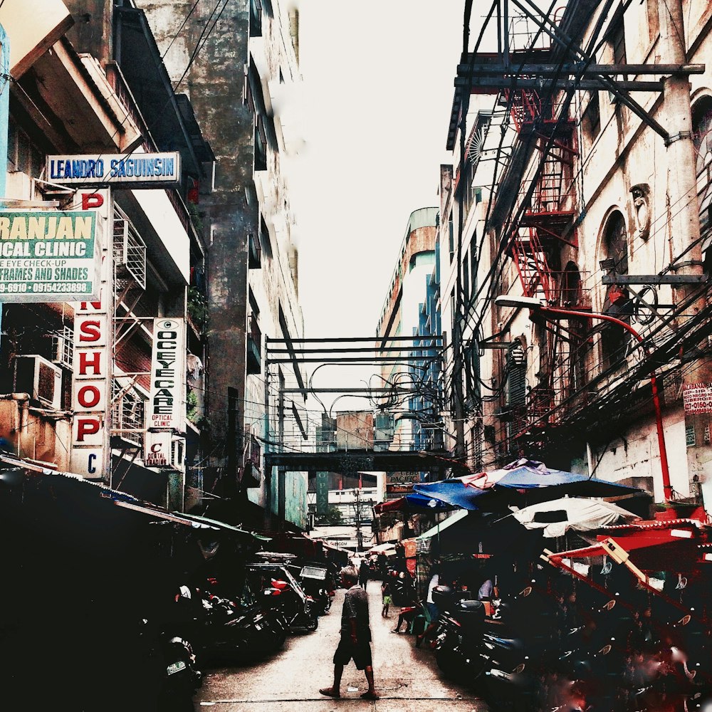 a man walking down a street next to tall buildings