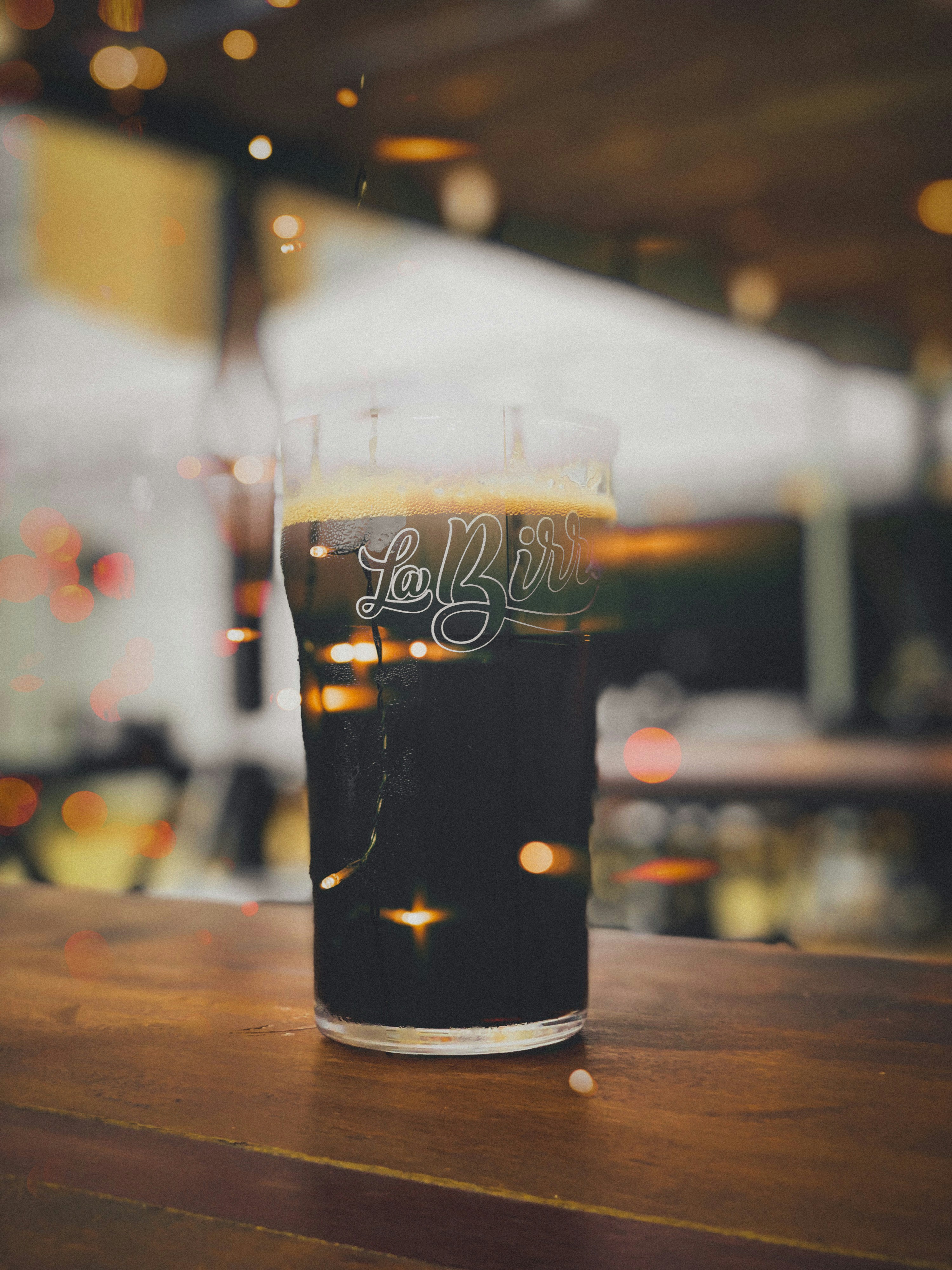 A glass of beer sitting on top of a wooden table photo – Free Goiânia ...