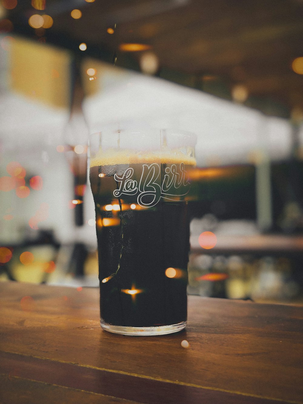 a glass of beer sitting on top of a wooden table