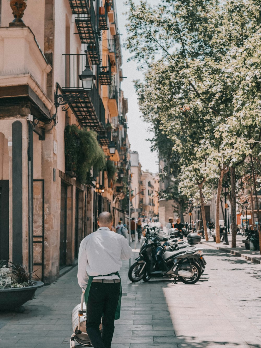 a man walking down a street next to parked motorcycles