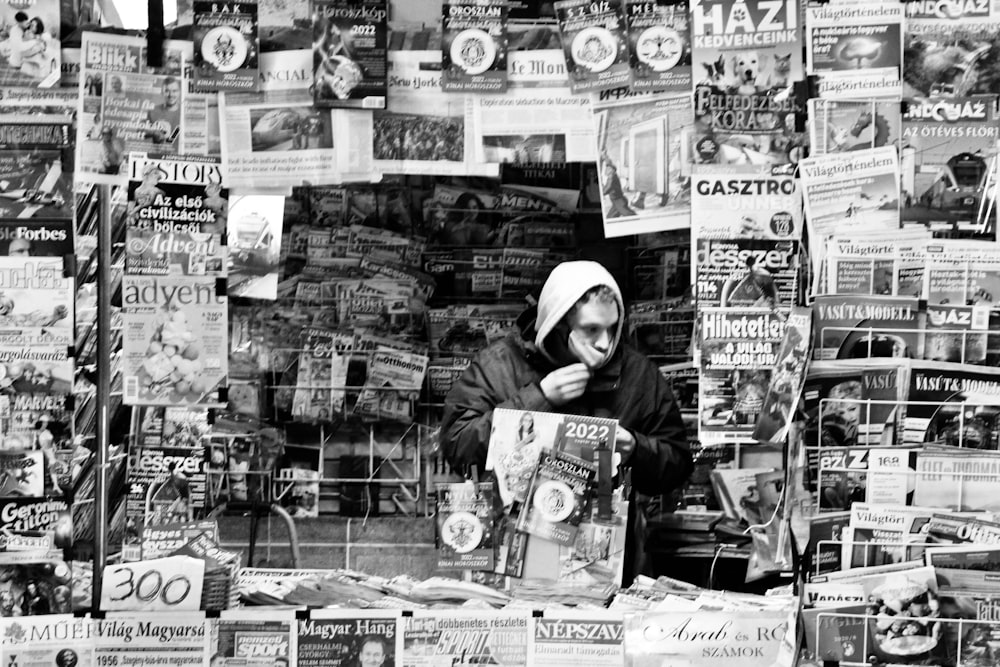 a woman sitting in front of a newspaper stand