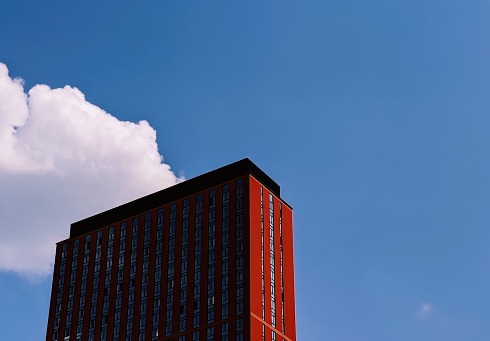 a tall red building sitting under a cloudy blue sky