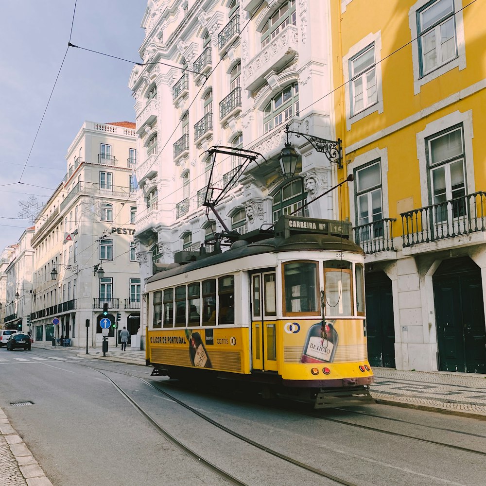 a yellow trolley car traveling down a street next to tall buildings