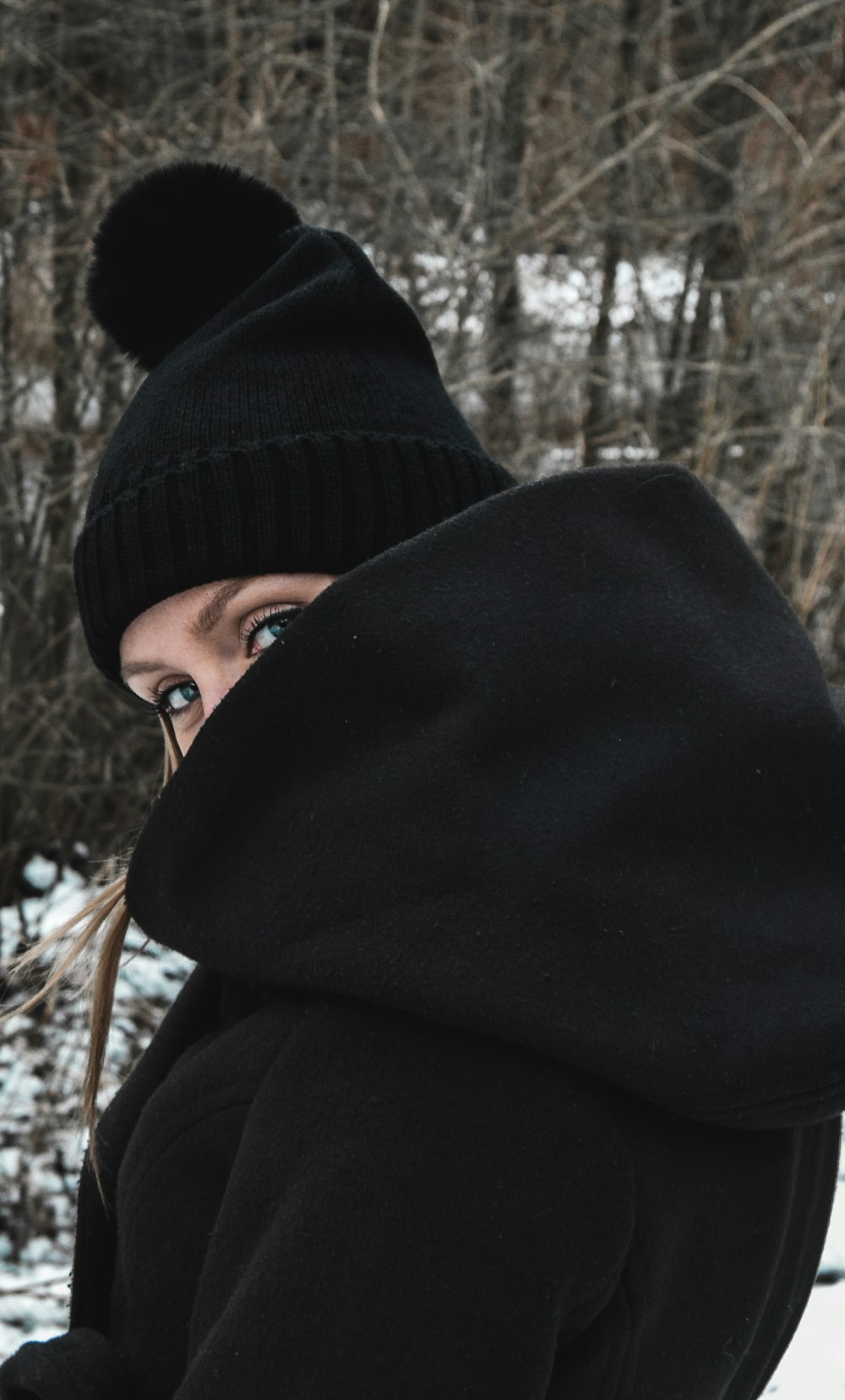 a woman wearing a black coat and a black hat