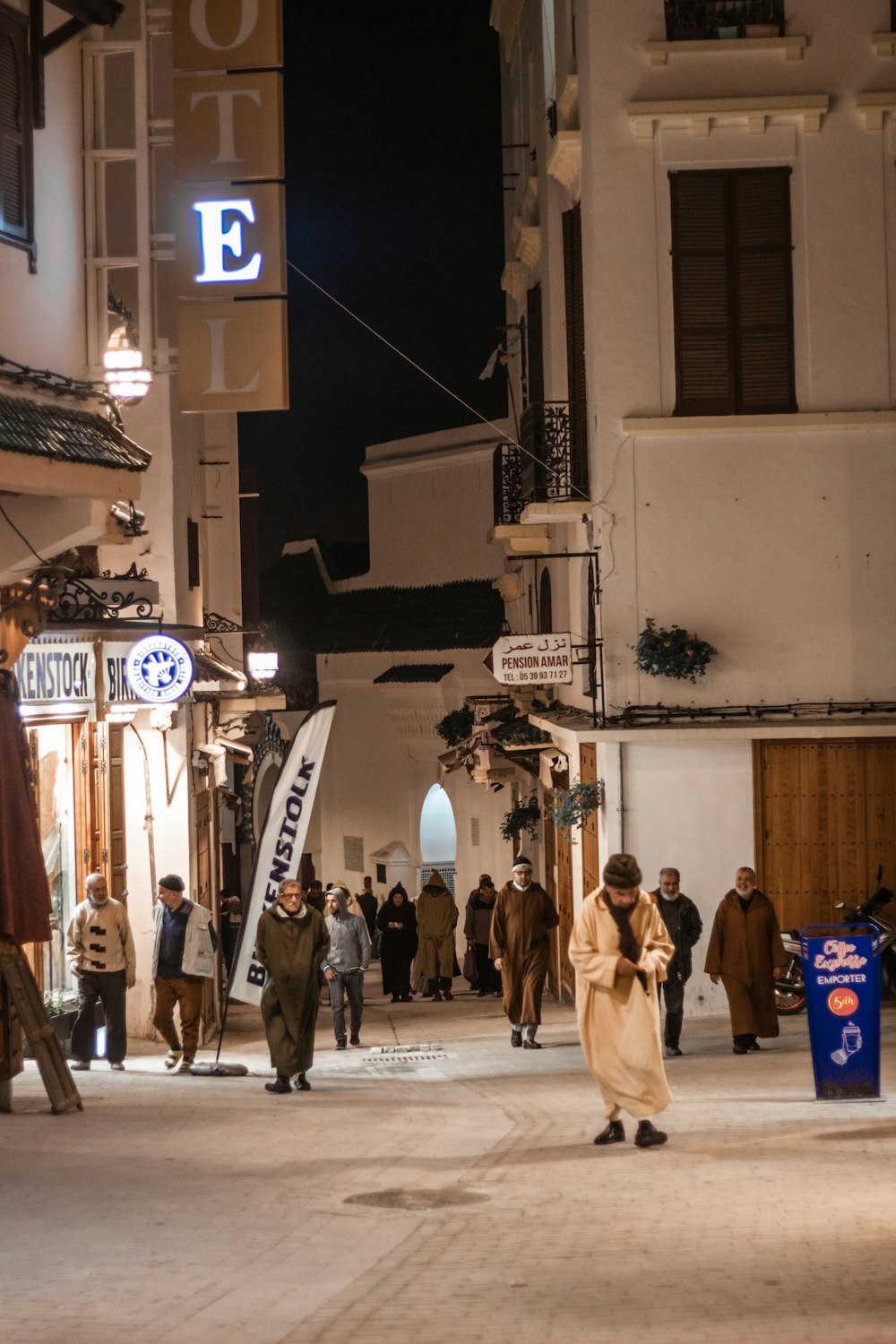 Un grupo de personas caminando por una calle junto a edificios altos