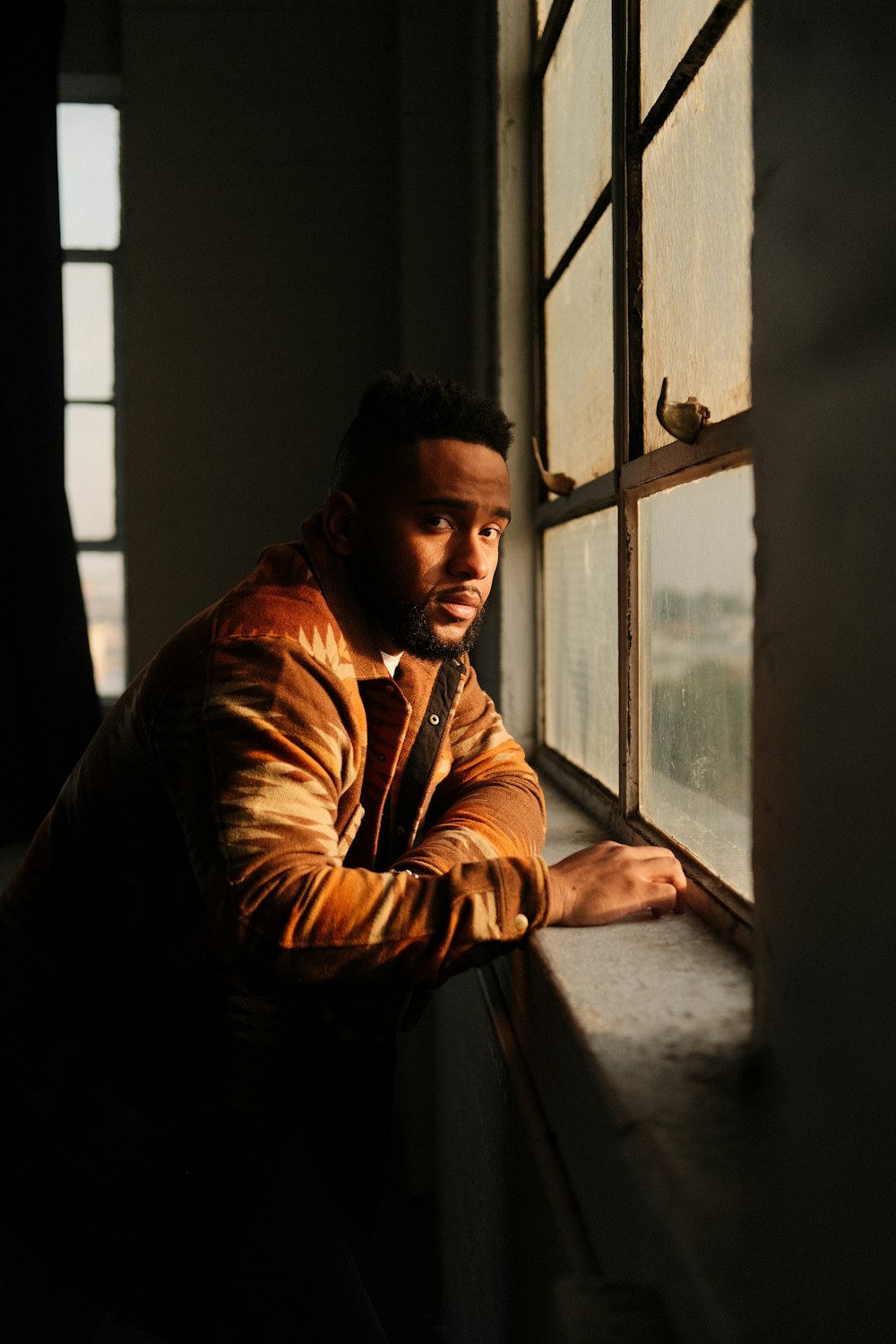 a man leaning against a window in a dark room