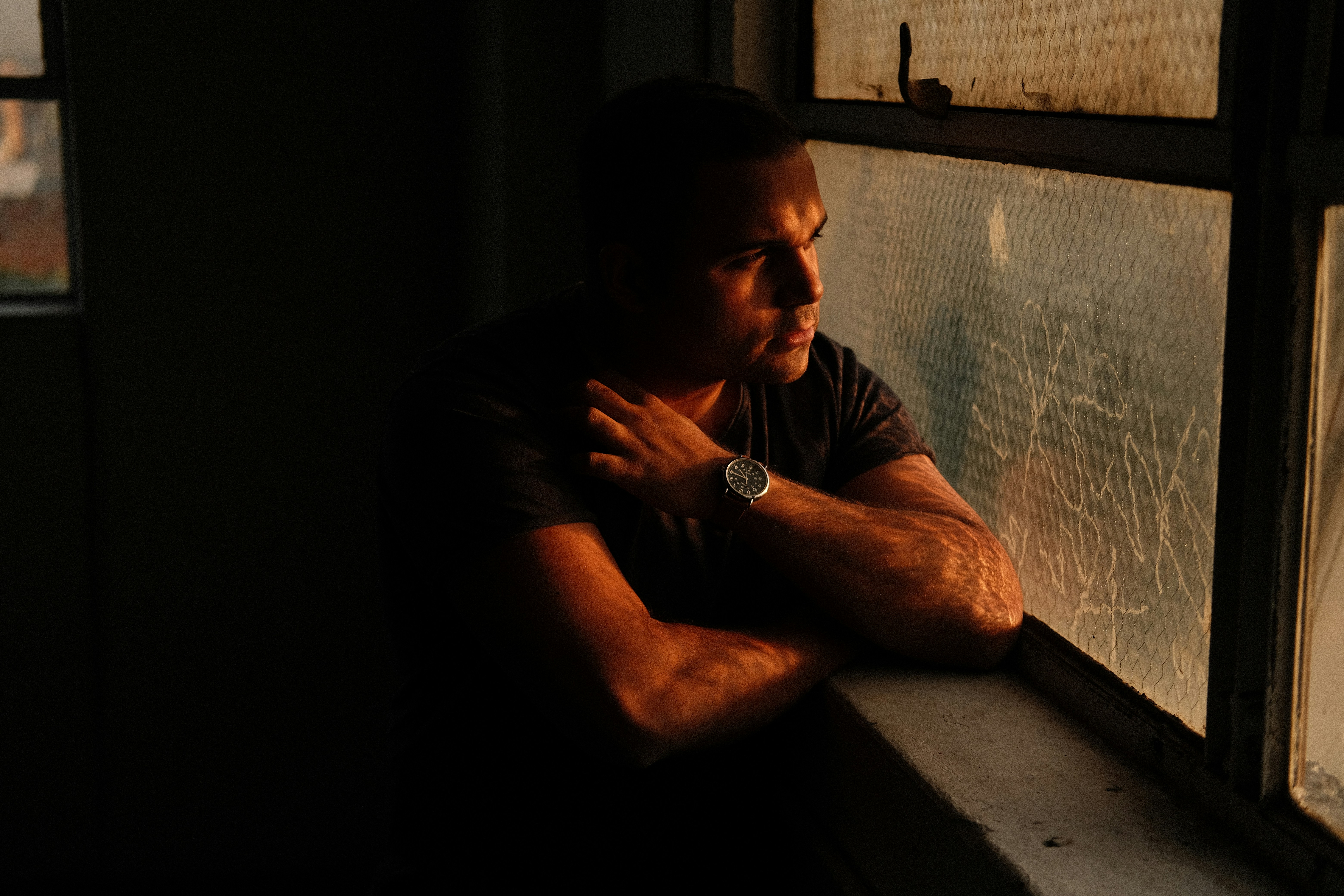 a man looking out of a window in a dark room