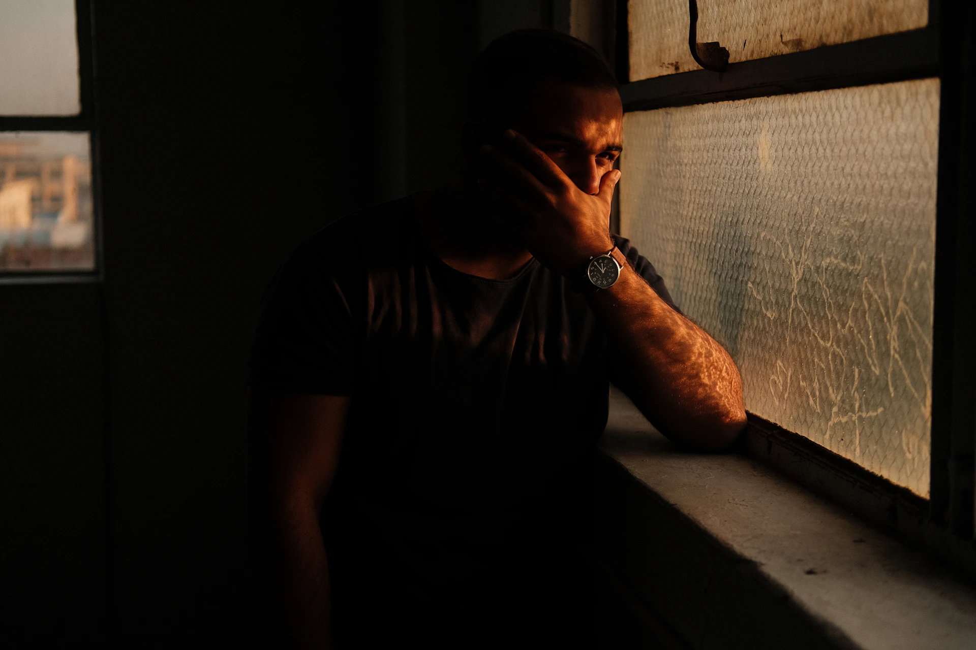 a man leaning against a window in a dark room