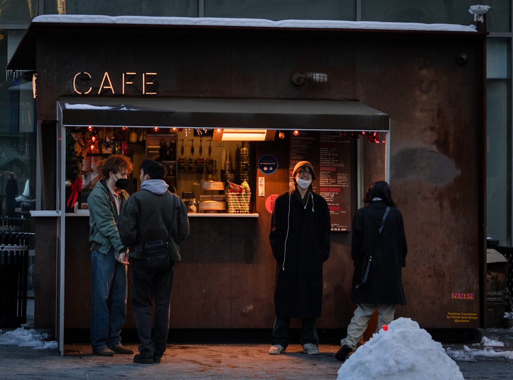a group of people standing outside of a cafe