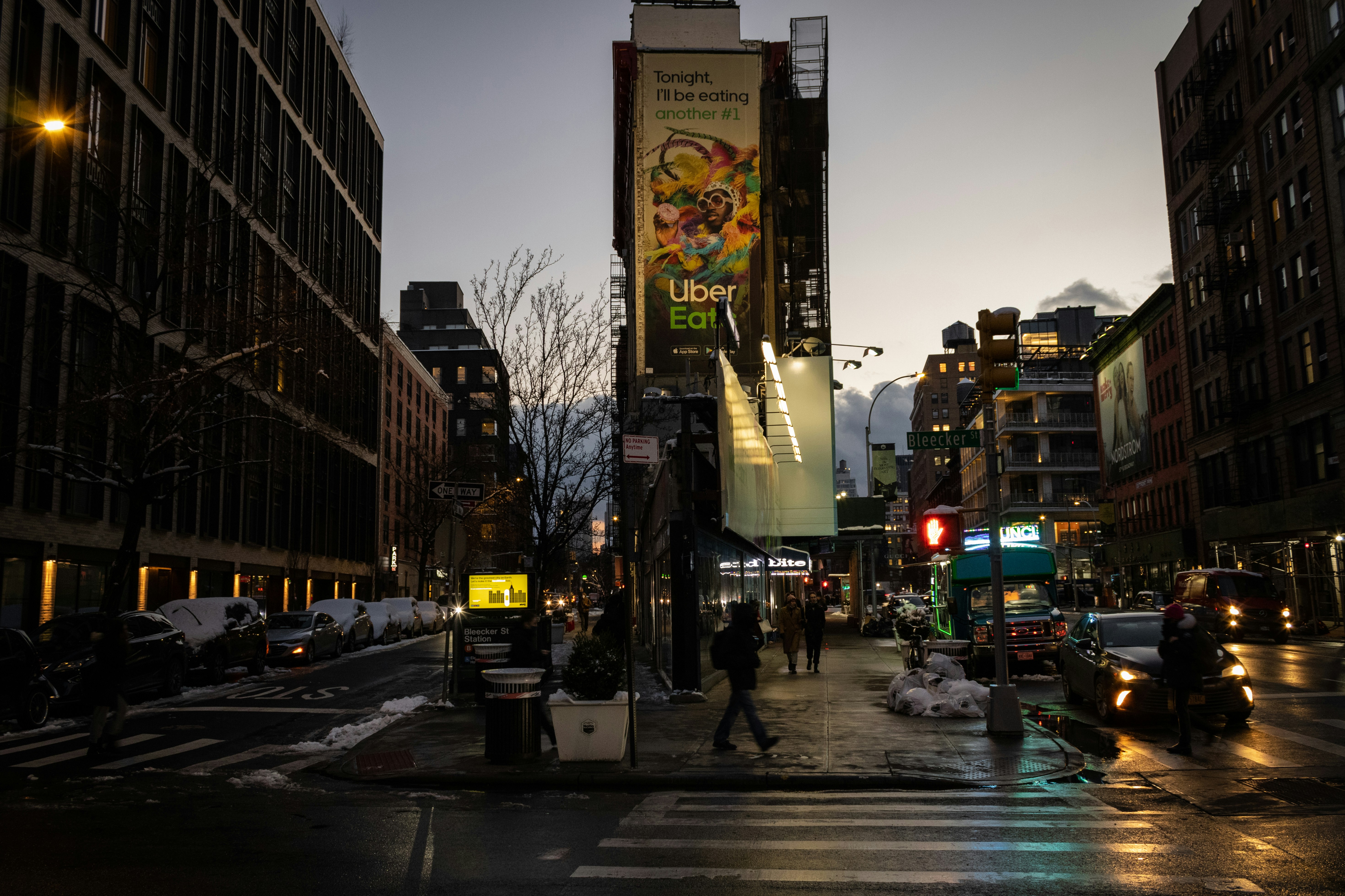 a city street at night with people crossing the street
