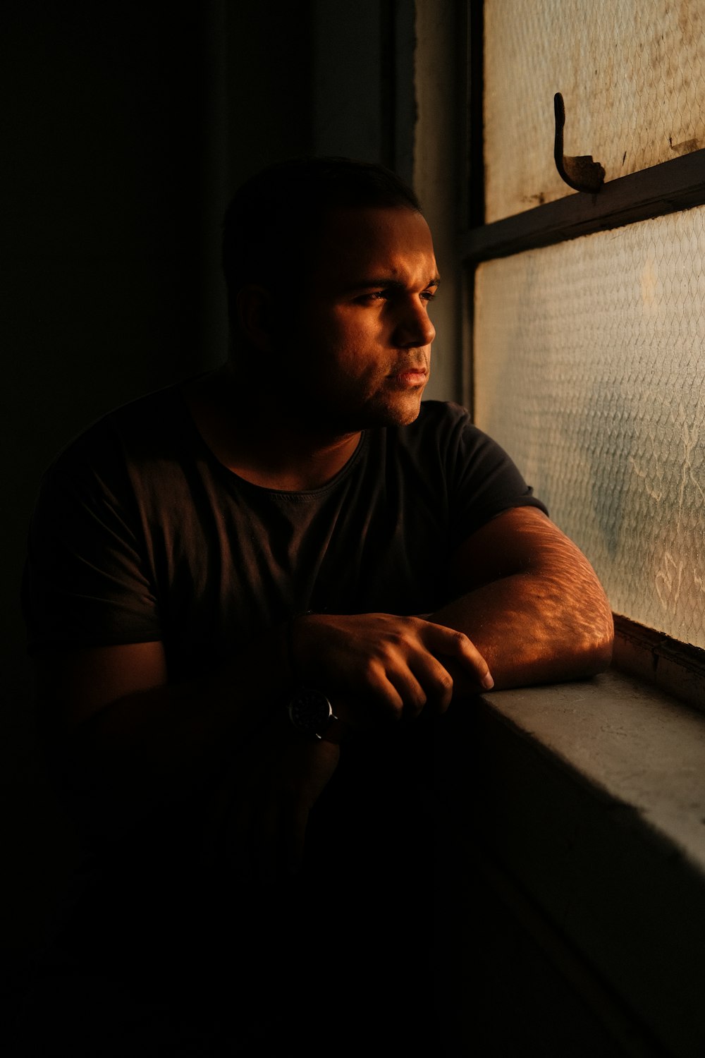 Un hombre mirando por una ventana en la oscuridad