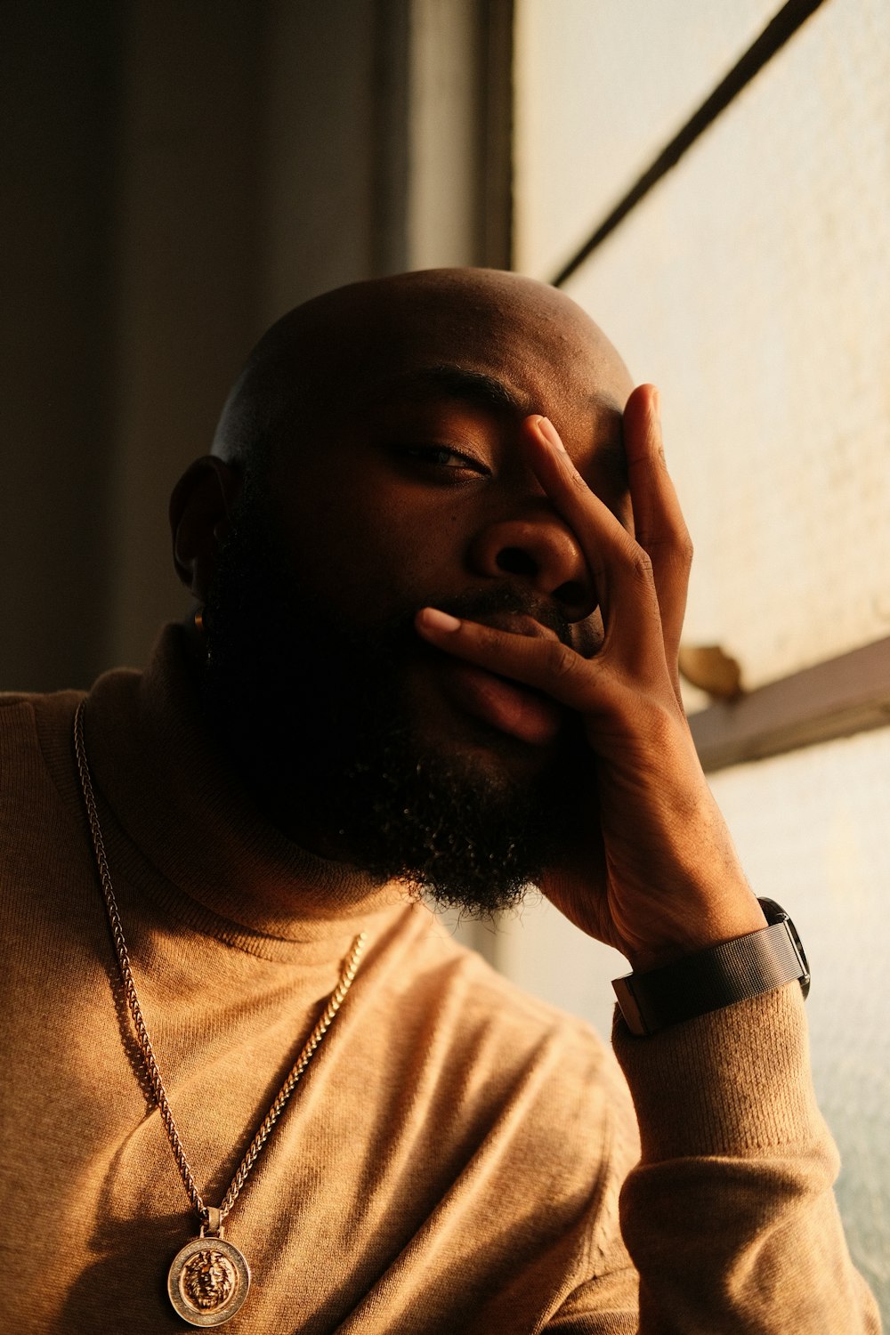 Un homme avec une barbe tient sa main contre son visage