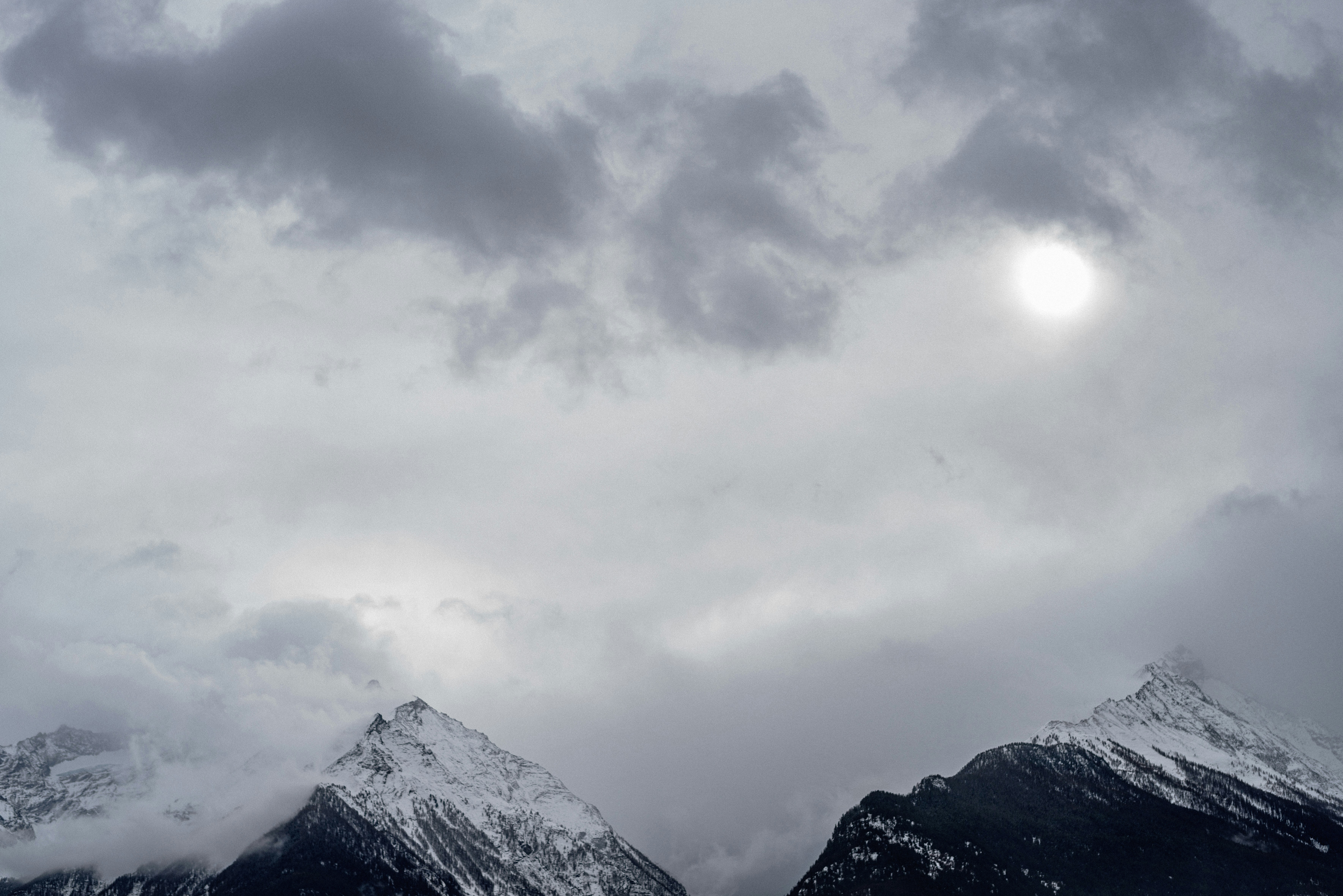 a couple of snow covered mountains under a cloudy sky