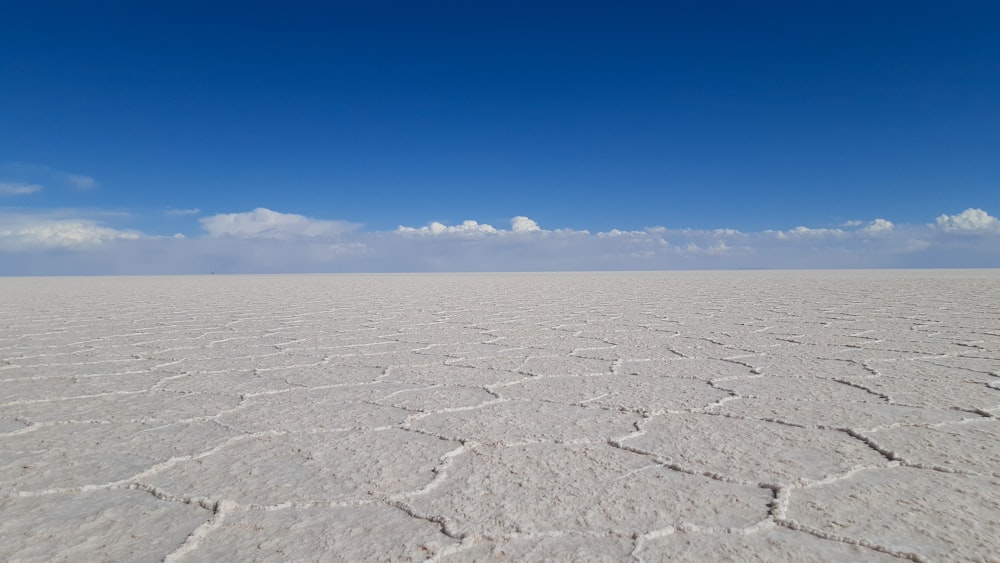 une vaste étendue de sable blanc avec un ciel bleu en arrière-plan