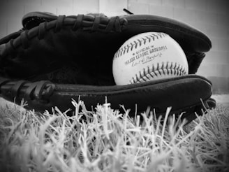 a black and white photo of a baseball in a baseball mitt