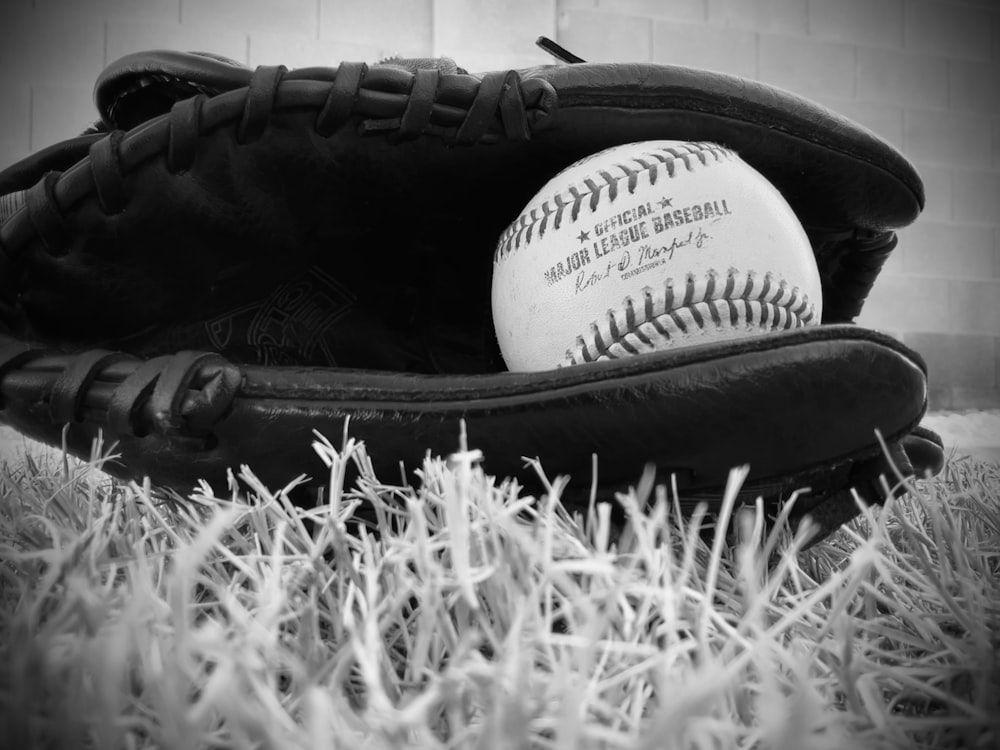 a black and white photo of a baseball in a baseball mitt
