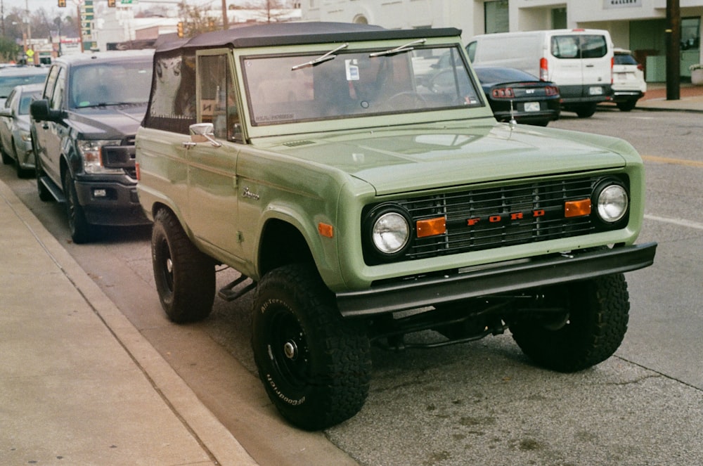 a green truck parked on the side of a road