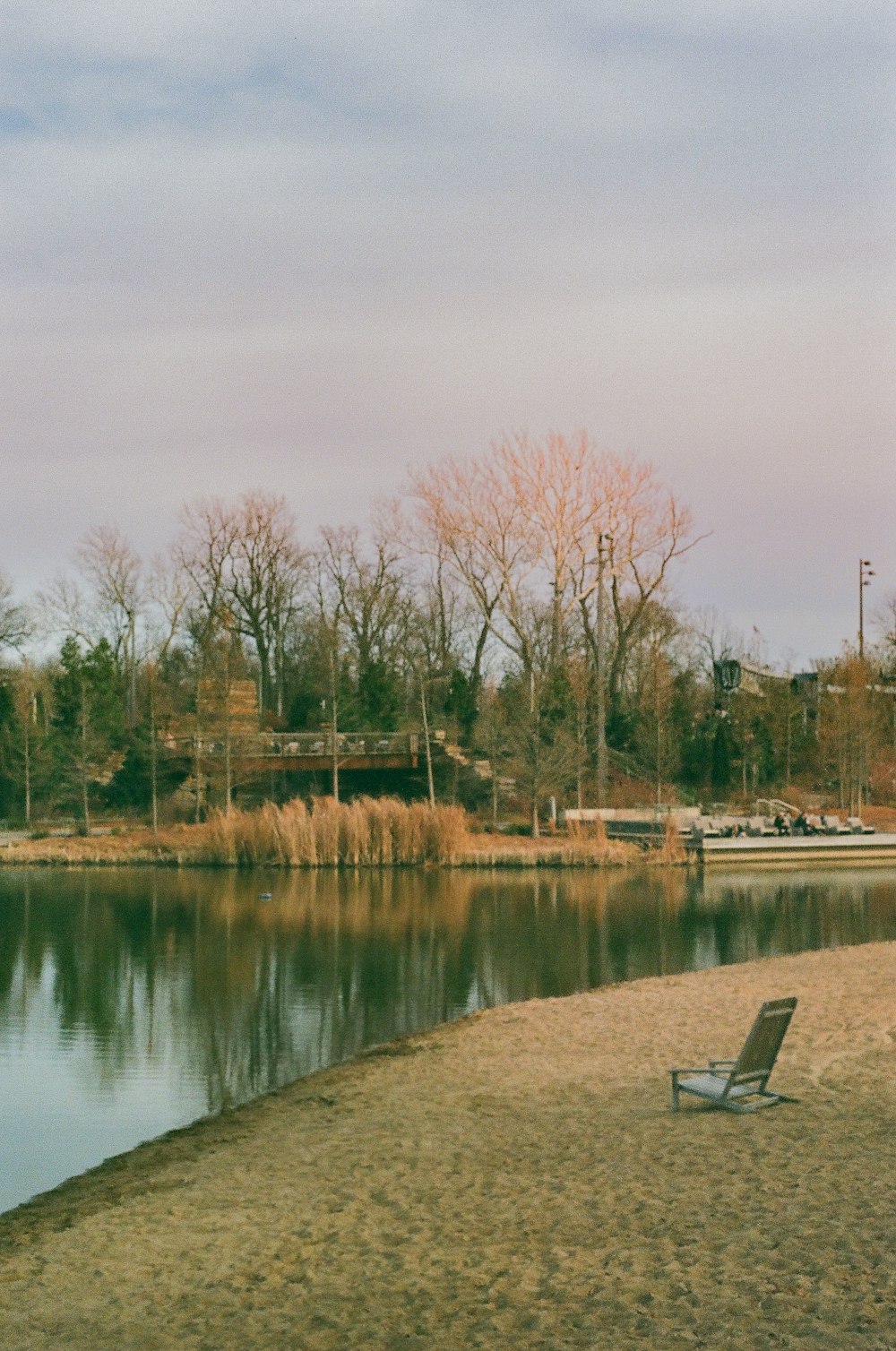 a lone chair sitting on the shore of a lake