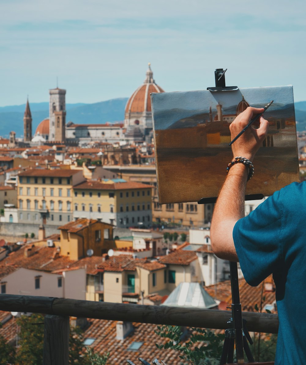 a man is painting a cityscape with buildings in the background