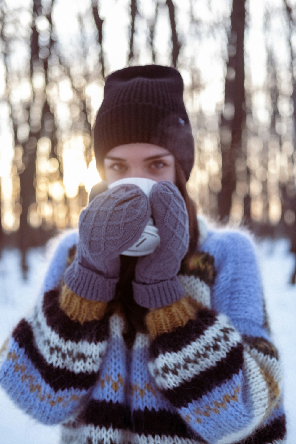 a woman in a hat and mittens covers her face with her hands