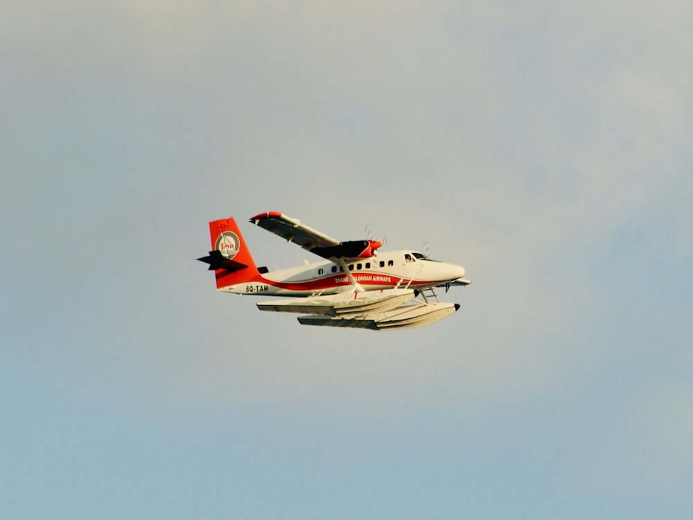 a red and white plane flying in the sky