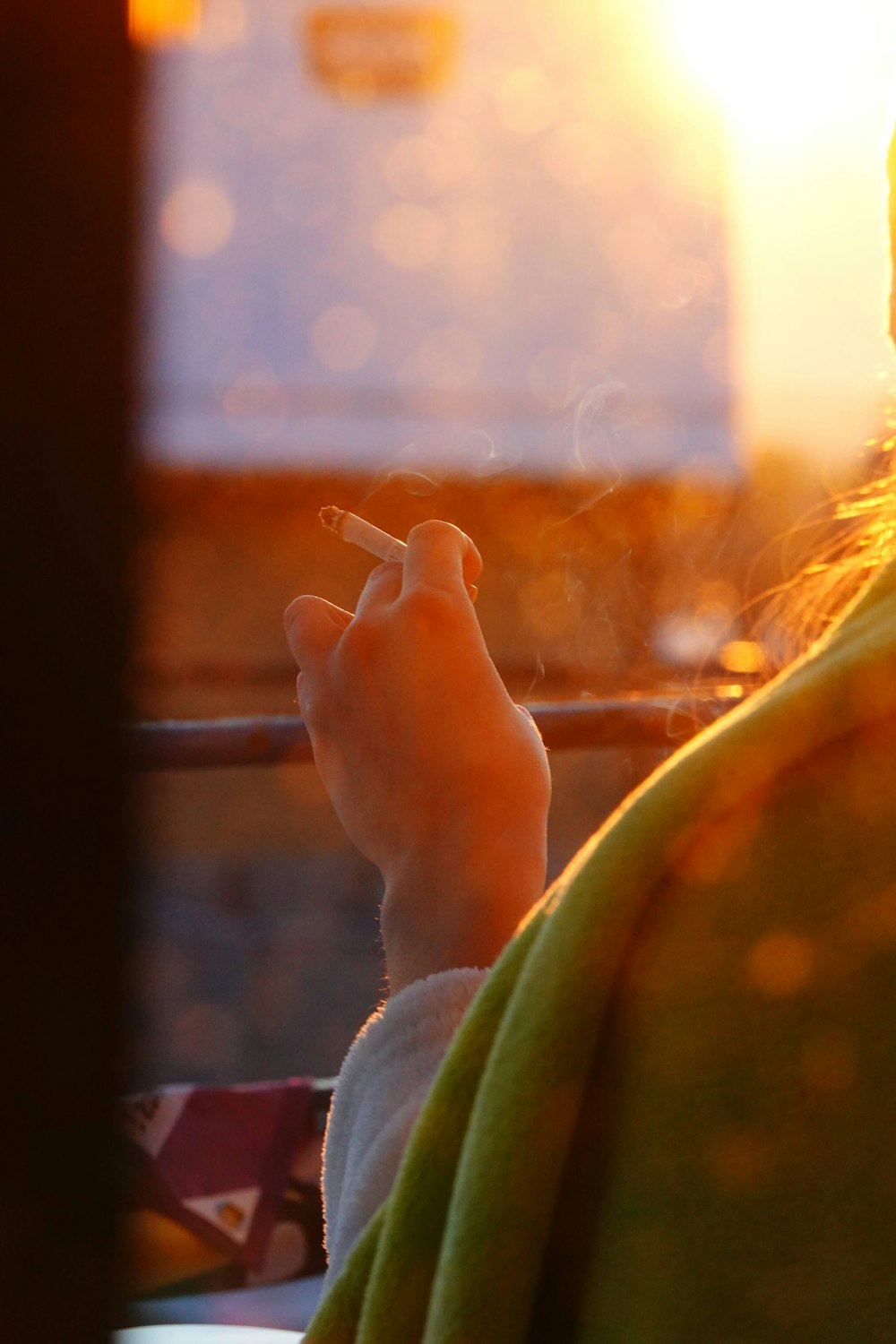 uma mulher que fuma um cigarro na frente do sol