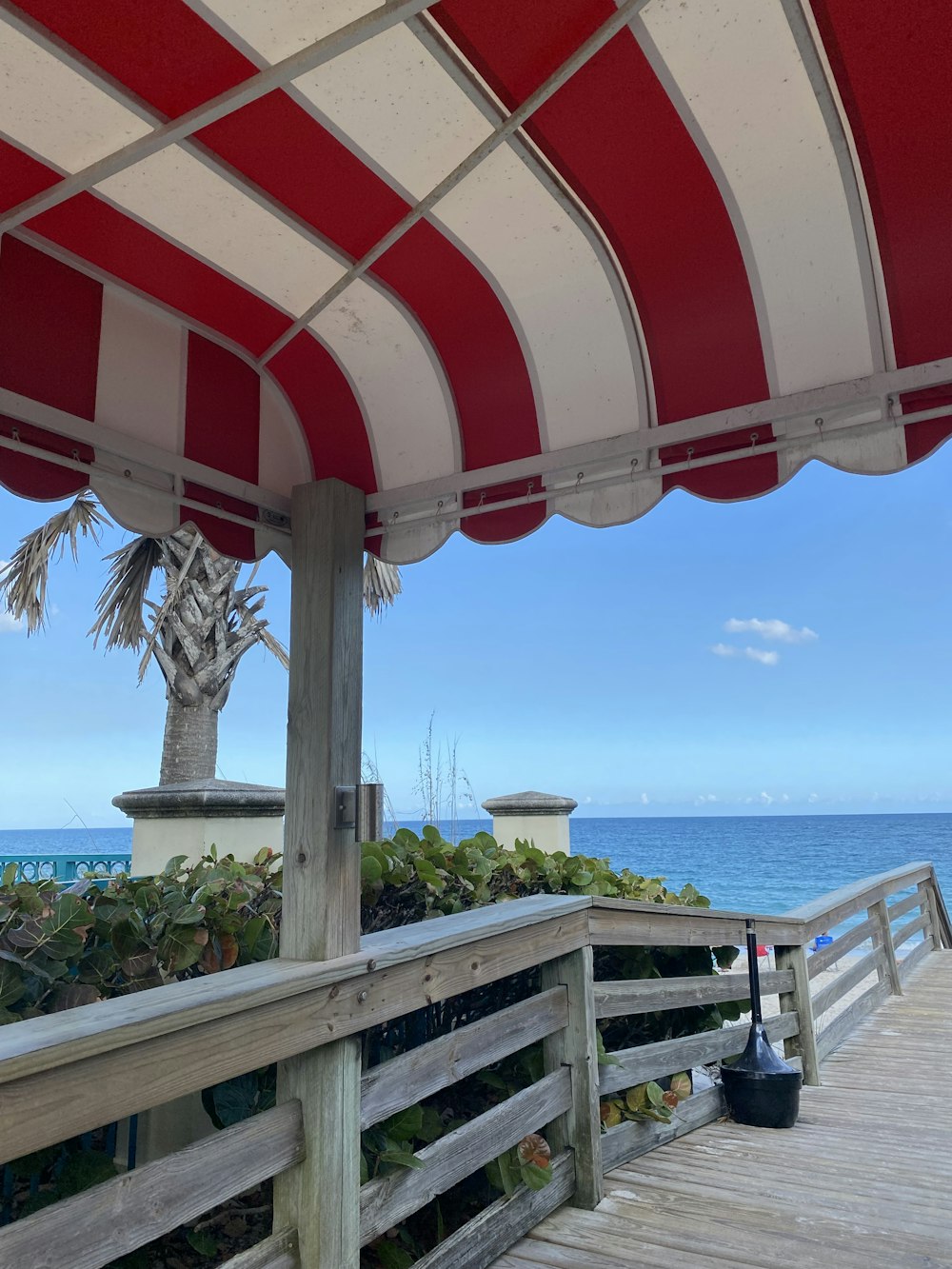 a red and white awning over a wooden deck next to the ocean
