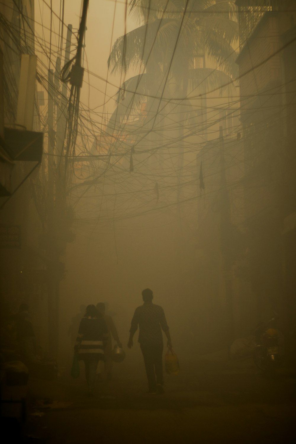 a couple of people walking down a street on a foggy day