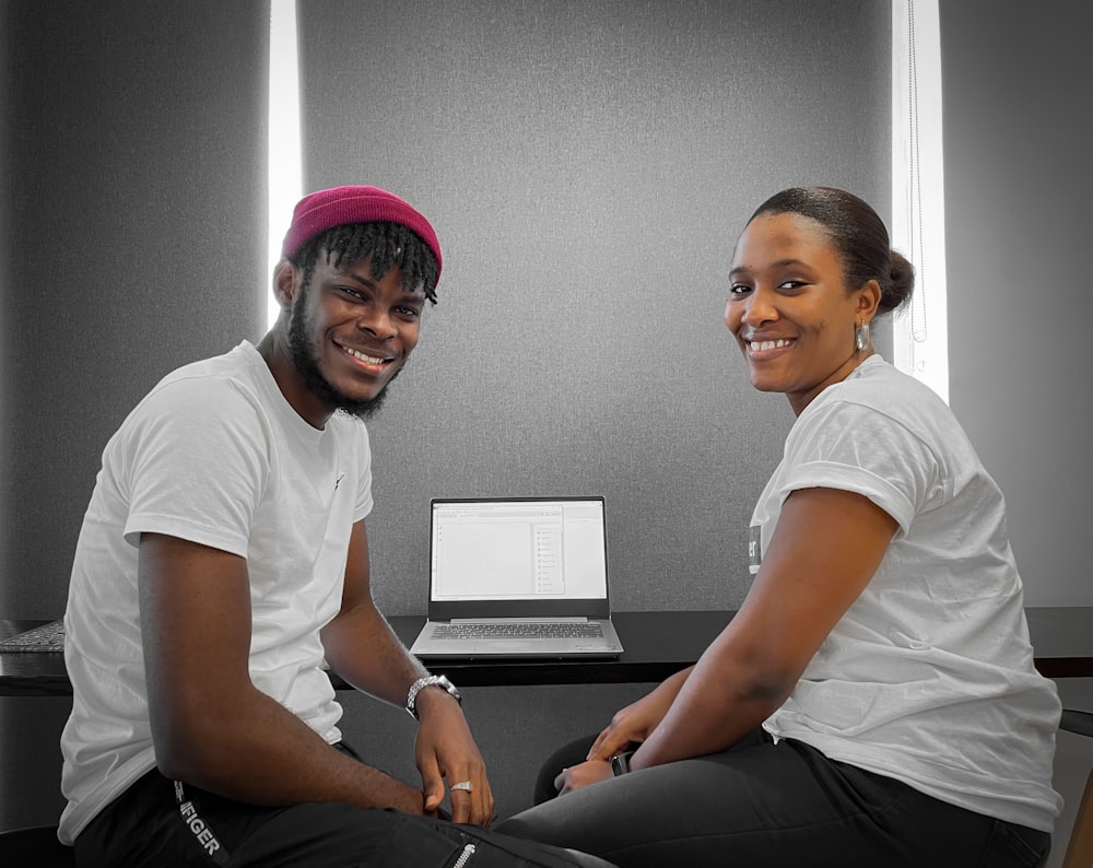 a man and a woman sitting next to each other in front of a laptop