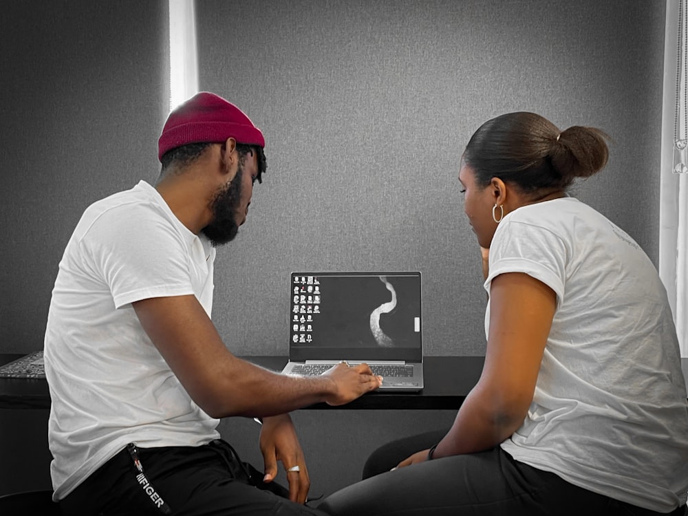 a man and a woman sitting at a table with a laptop